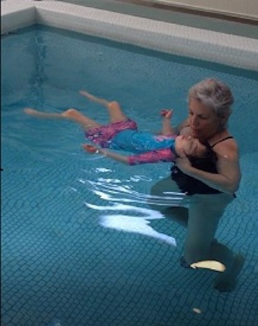 Camilla swims in the pool with her grandma.