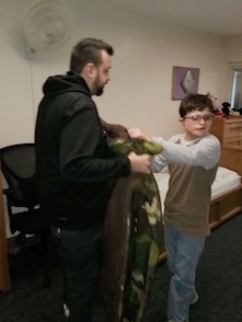 Omar helps Nathanial put on his jacket.